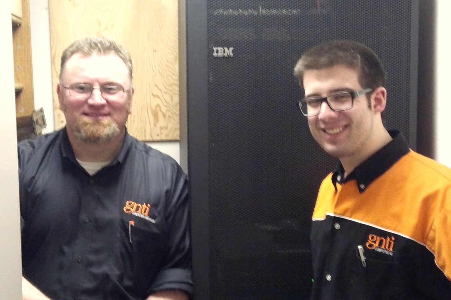 Stelian Paraschiv and a GNTI technician in company shirts beside a client's server rack
